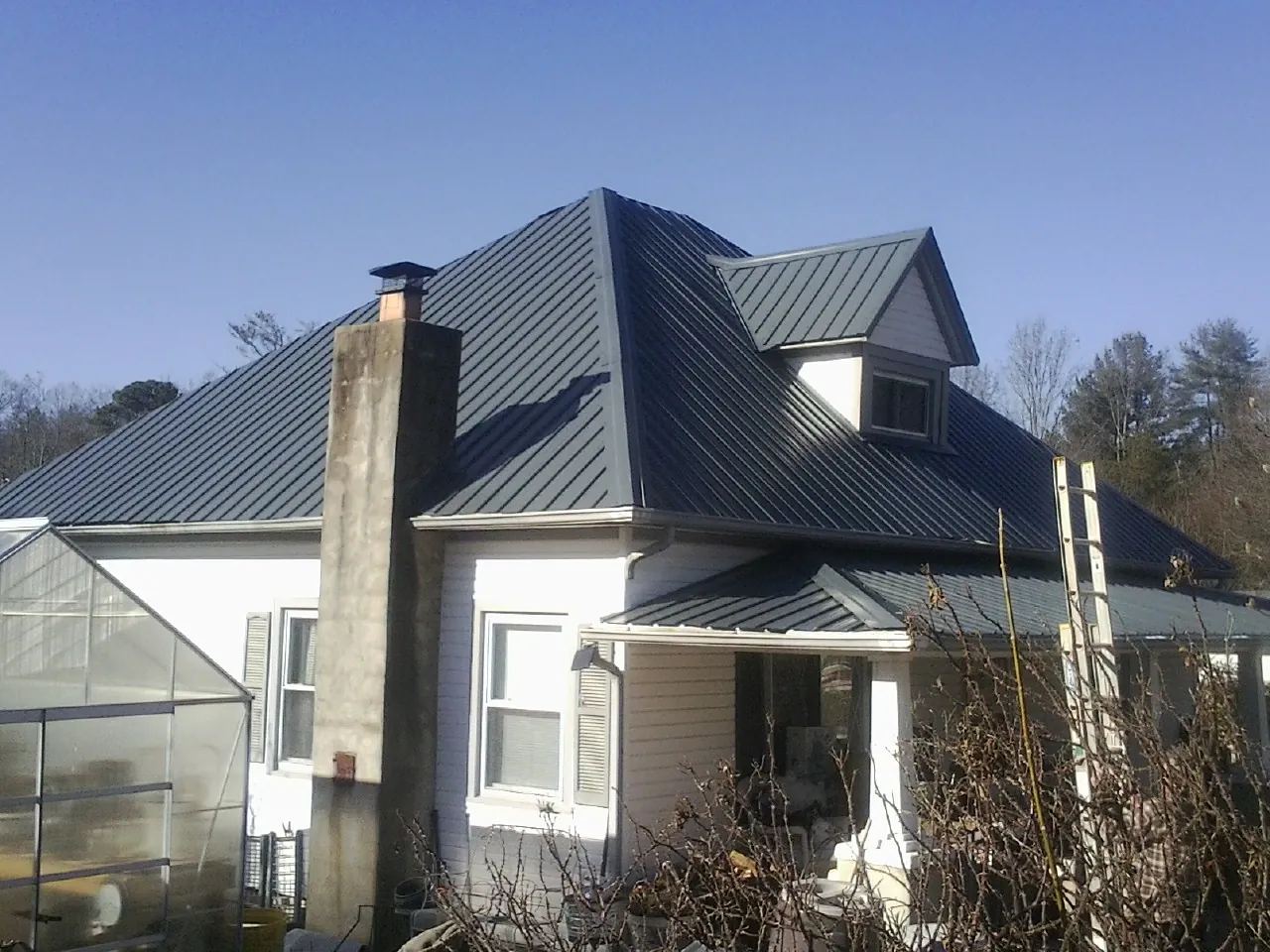 Dark blue standing seam metal roof on a white farmhouse with dormer — Slate & Tile Roof Repair by Roofing Brothers in Wethersfield