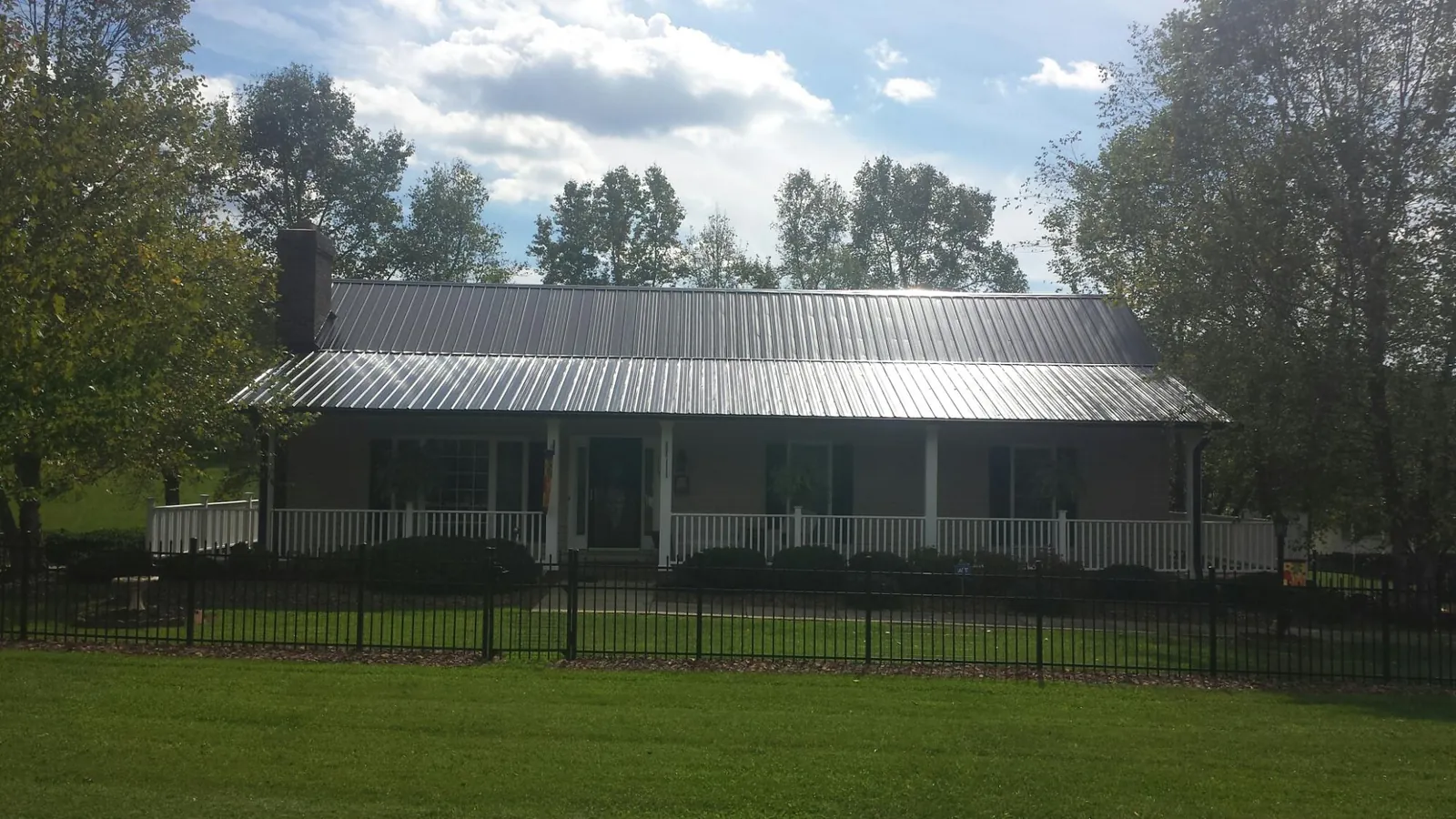 Gray metal roof on a brick ranch with a full width front porch — Gutter Guard Installation work by our crew in Wethersfield