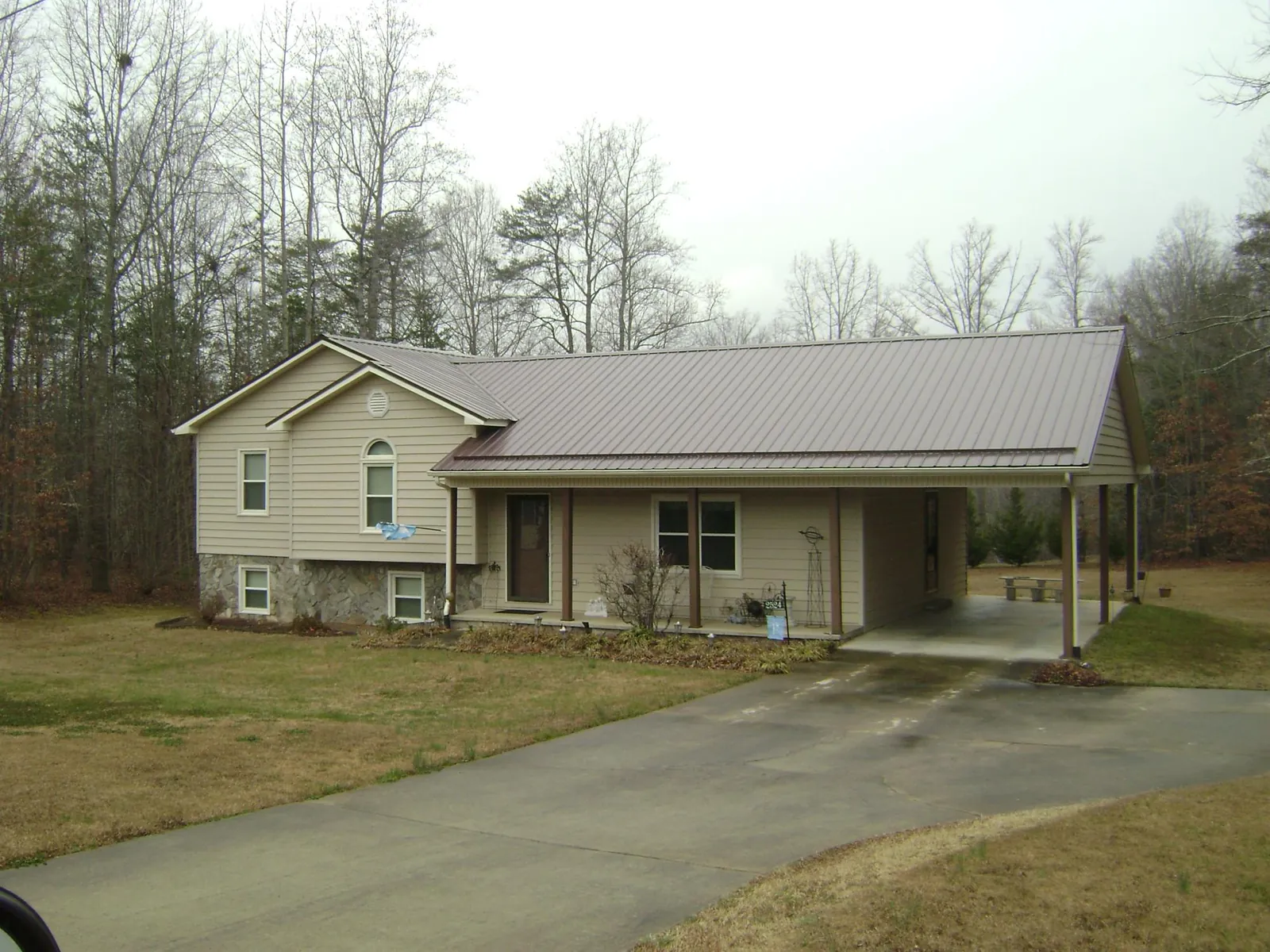 Brown metal roof on a tan split level home with an attached carport in Wethersfield
